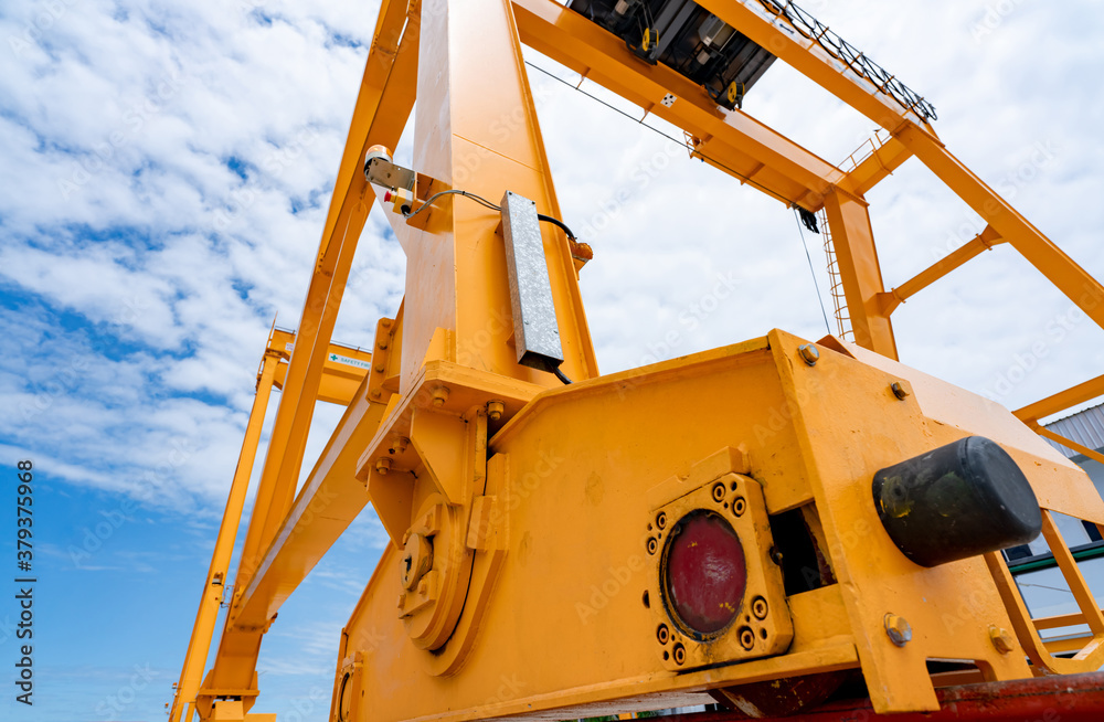 Bottom view of yellow gantry crane against blue sky at port. Gantry