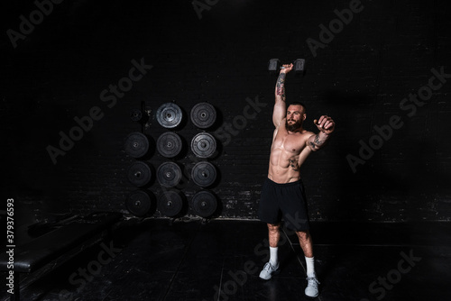 Slika na platnu Young sweaty strong fit muscular man with big muscles doing snatch or jerk worko