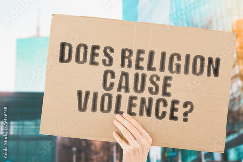 Fotografia The question  Does religion cause violence?  on a banner in men's hand with blurred background