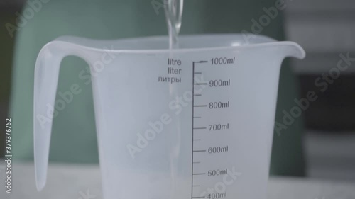 the cook adds boiled water to a measuring Cup