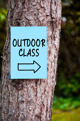 Outdoor class sign with an arrow written on paper on a tree in the forest. Outdoor education.