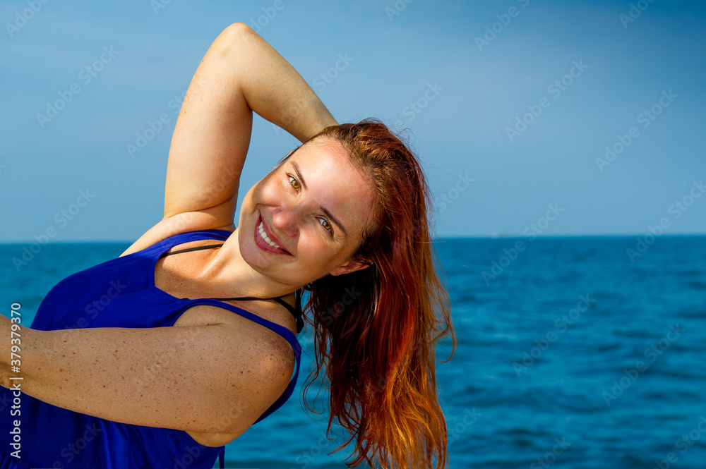 Happy smiling girl on the background of the blue sea.Portrait of smiling woman at the sea.