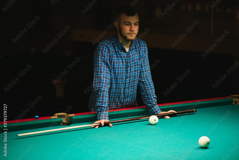 Fototapeta premium Young man playing billiard. Spending free time on gambling