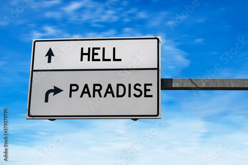 White road sign with words hell and paradise against blue sky background.