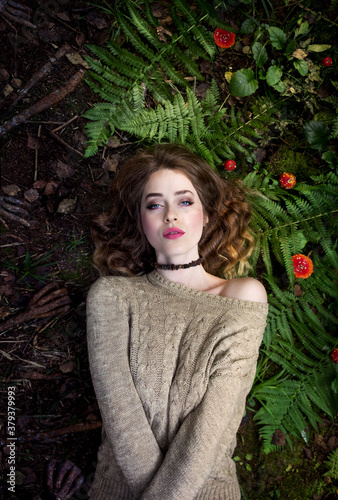 Gothic portrait. The girl lies on the grass. Girl in fern and amanita.