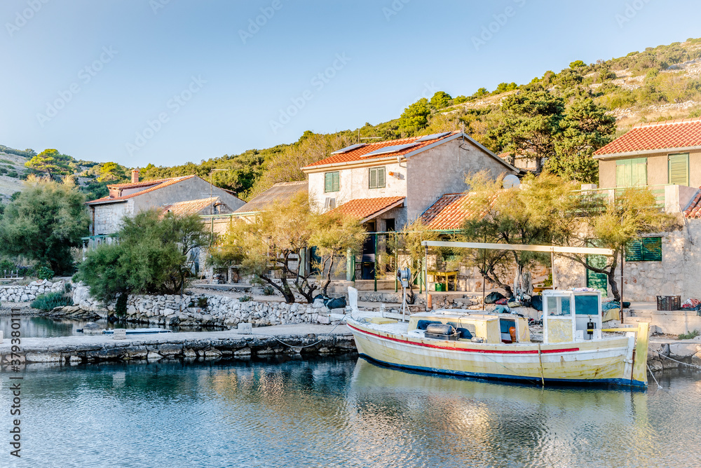Yellow wooden boat on the pier in the bay of the Adriatic sea near the fishing village in the evening in Lavsa, Croatia Yellow wooden boat on the pier in the bay of the Adriatic sea near the fishing village in the evening in Lavsa, Croatia