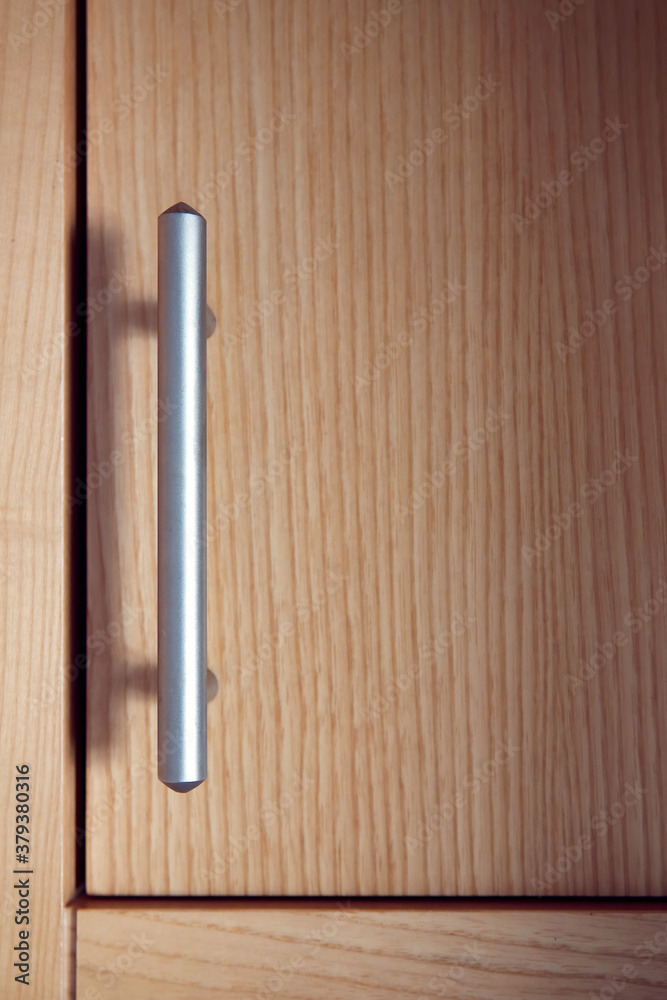 Satin nickel plated door handle on an alder wood cupboard or cabinet. Satin nickel plated door handle on an alder wood cupboard or cabinet.