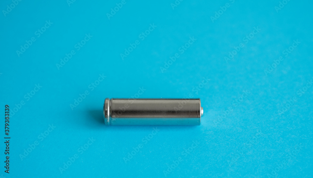 A single rechargeable battery on blue background. Silver alkaline AA battery for different device. Energy. A single rechargeable battery on blue background. Silver alkaline AA battery for different device. Energy.