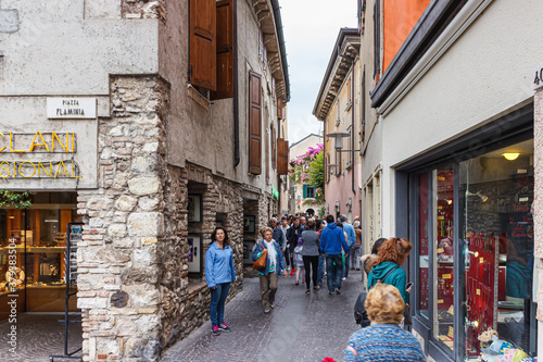 Tourists and residents walk along Via Vittorio Emanuele street in old part of the Sirmione town in Lombardy, northern Italy