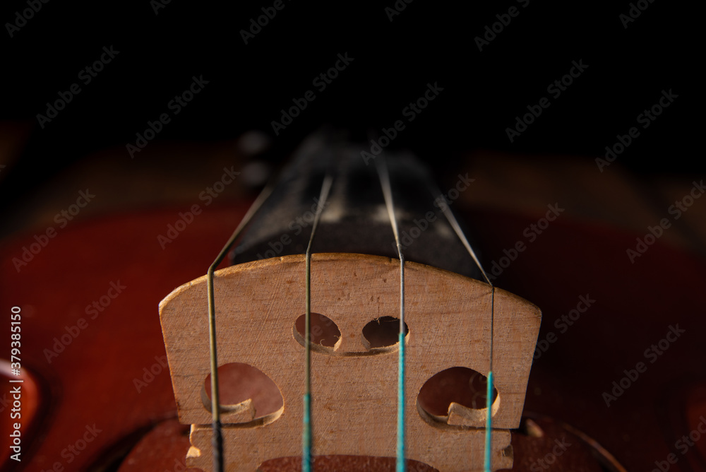 Details of an old and beautiful violin on a rustic wooden surface and black background, low key portrait, selective focus. Details of an old and beautiful violin on a rustic wooden surface and black background, low key portrait, selective focus.