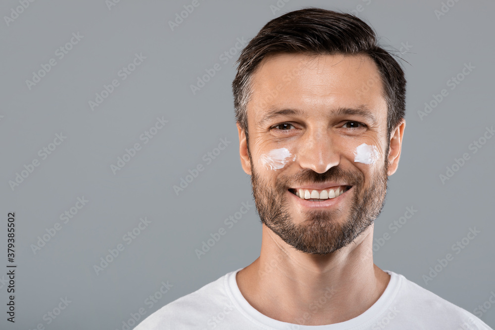 Young man with face cream on cheeks Young man with face cream on cheeks