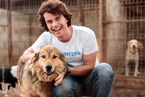 Cheerful volunteer with dog in shelter photo