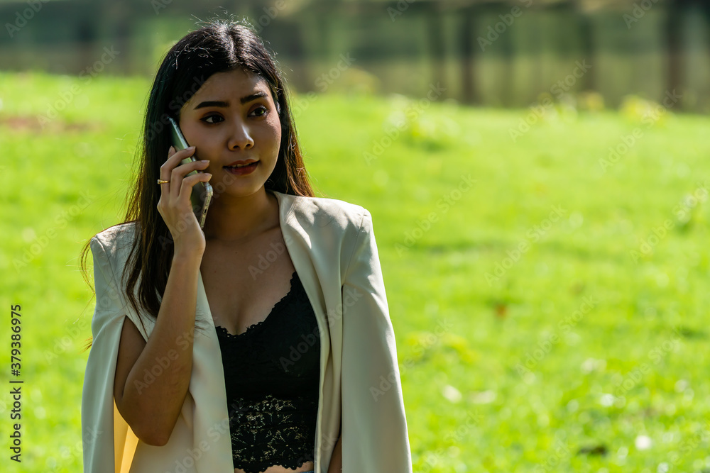 Asian Business Woman Talking with customer on mobile phone in public park Asian Business Woman Talking with customer on mobile phone in public park
