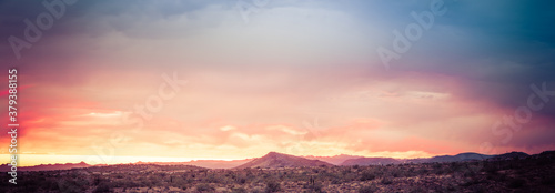 A dramatic cloudy panorama sunset in the desert of Arizona with mountains.