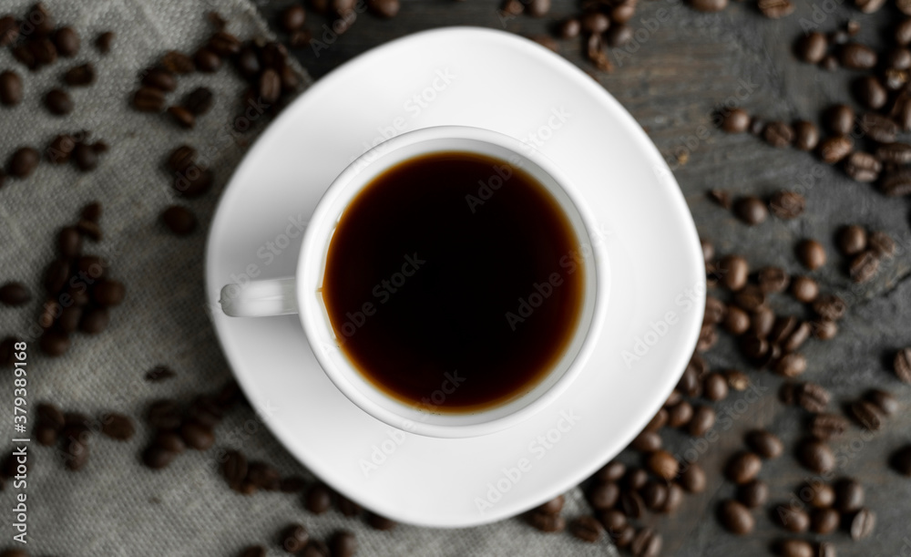 Coffee cup with roasted coffee beans on wooden table background. Mug of black coffe with scattered coffee beans on a wooden table. Fresh coffee beans. Coffee cup with roasted coffee beans on wooden table background. Mug of black coffe with scattered coffee beans on a wooden table. Fresh coffee beans.