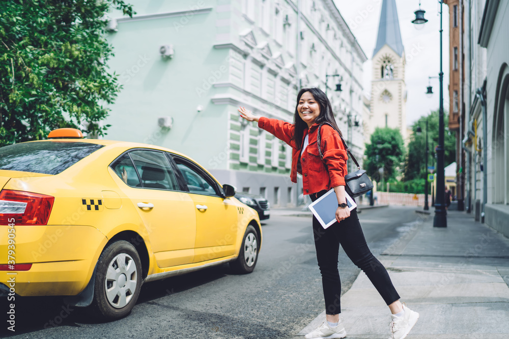 Smiling ethnic woman with tablet catching cab on street Smiling ethnic woman with tablet catching cab on street