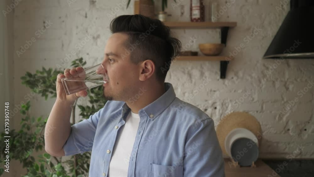 Smiling young healthy bearded guy holding glass, drinking pure fresh water. Smiling young healthy bearded guy holding glass, drinking pure fresh water.
