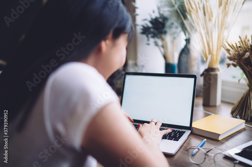 Crop woman typing on laptop keyboard at home