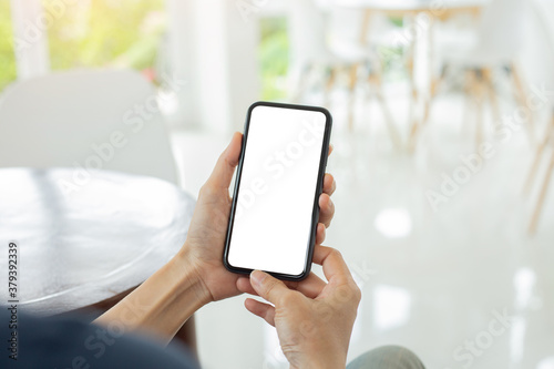 cell phone mockup blank white screen.woman hand holding texting using mobile on desk at coffee shop.background empty space for advertise.work people contact marketing business,technology © panitan