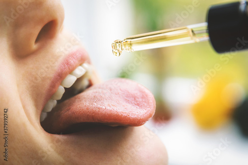 herbal alternative medicine and dietary supplements - woman taking cbd hemp oil drops in mouth from dropper. medical cannabis photo