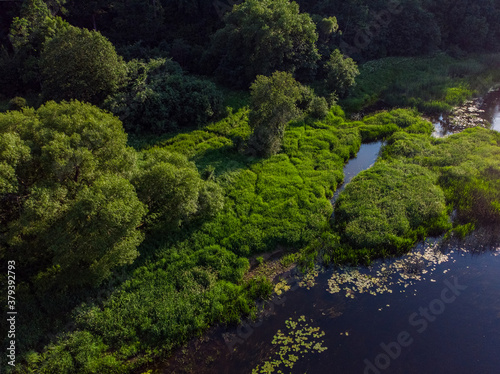 Areal countryside view o river Venta flowing through lovely environment with trees on a warm summer day.