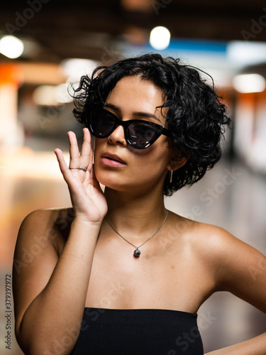 Vertical portrait of a stylish young female with fancy sunglasses wearing a strapless top