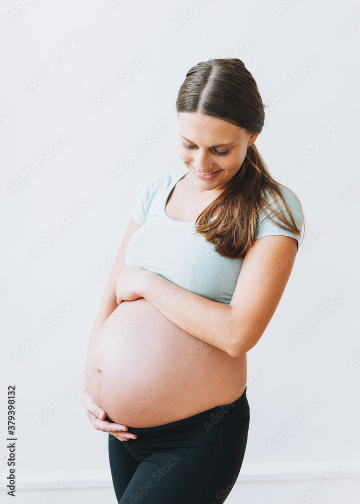 Young pregnant woman in sport wearing isolated on the white background Young pregnant woman in sport wearing isolated on the white background