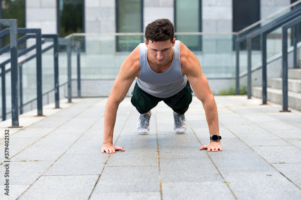Athletic man doing push ups, urban workout concept