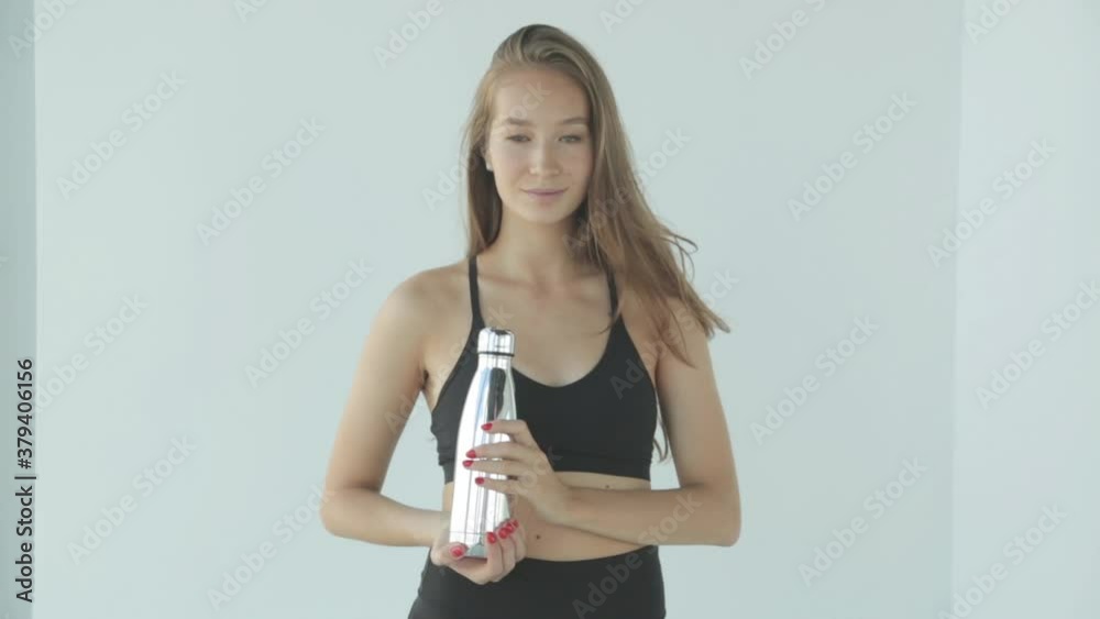 Close-up portrait of a sporty girl with a shaker. The girl smiles and laughs, looking at the camera on a white background. Close-up portrait of a sporty girl with a shaker. The girl smiles and laughs, looking at the camera on a white background.