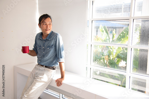 Man standing smile in the morning with red cup of coffee