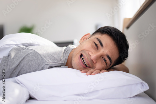 asian guy with braces wake up with smile on his bed