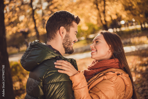 Photo of affectionate trust couple girl look into boyfriends face in fall october forest park wear outerwear coats