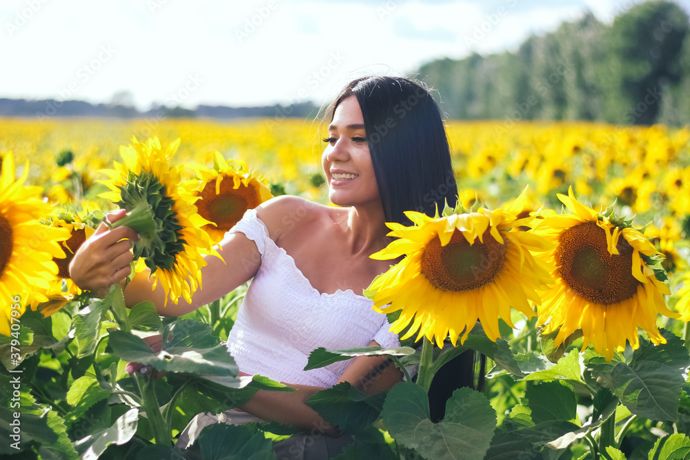 Beautiful brunette woman in a white top on the field with sunflowers. Yellow sunflowers. Close plan. Beautiful brunette woman in a white top on the field with sunflowers. Yellow sunflowers. Close plan.