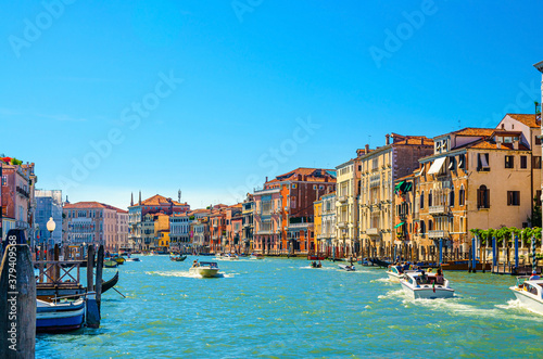 Venice cityscape with Grand Canal waterway, Venetian architecture colorful buildings, gondolas and yacht boats sailing Canal Grande, blue sky in sunny summer day. Veneto Region, Northern Italy.