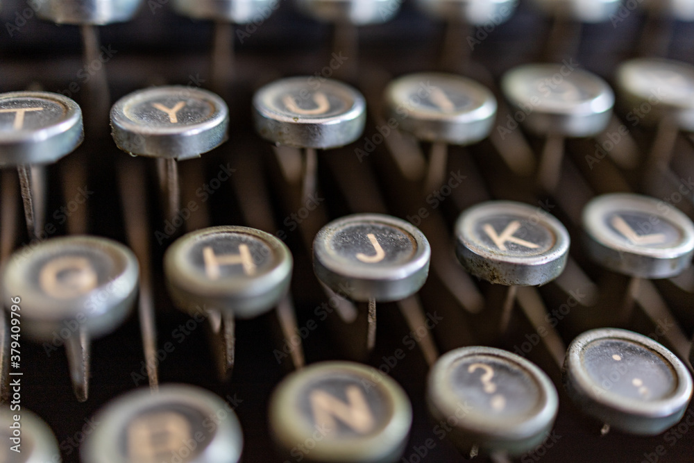 Selective focus close up on the keys of a black, vintage typewriter of the past century. Focus on j letter, blurred background. Selective focus close up on the keys of a black, vintage typewriter of the past century. Focus on j letter, blurred background.
