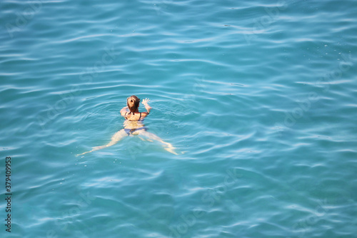 Fototapeta Naklejka Na Ścianę i Meble -  Woman in bikini swimming in the blue sea, aerial view. Relaxation on the water, beach vacations