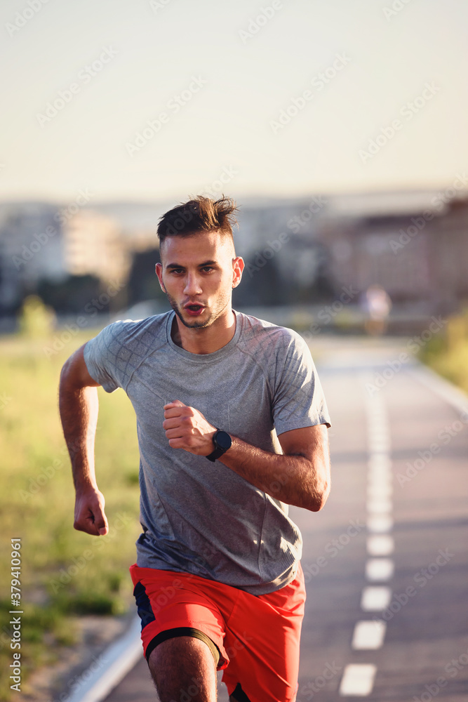 Sports man running fast outdoors on a race track Sports man running fast outdoors on a race track