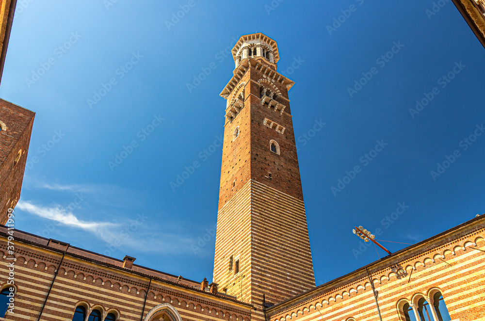 Torre dei Lamberti clock tower of Palazzo della Ragione palace building in Piazza Delle Erbe square in Verona city historical centre, Courtyard Of The Old Market, blue sky, Veneto Region, Italy