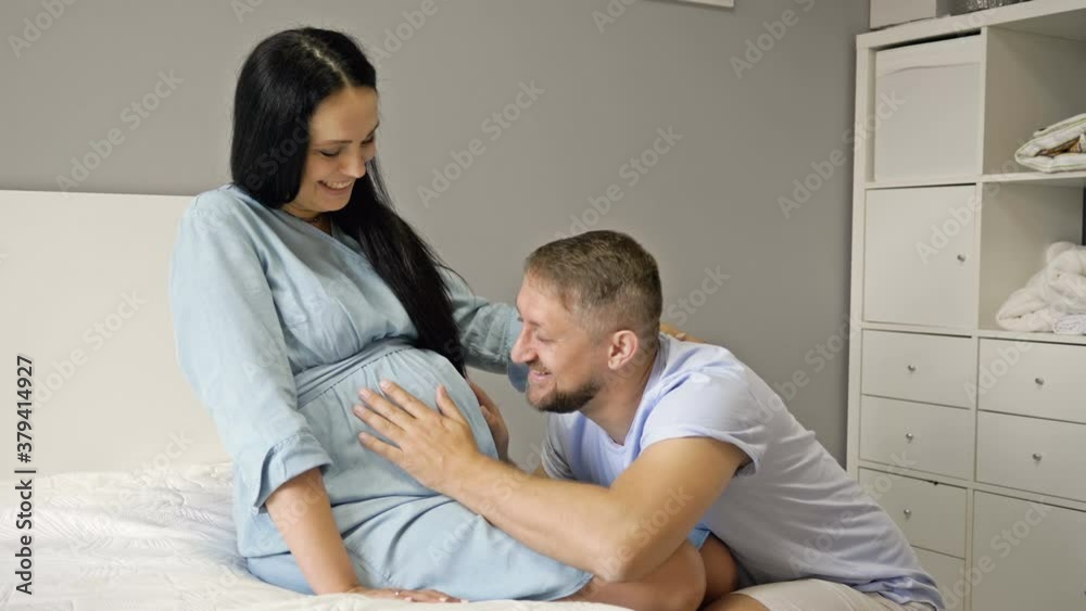 Happy husband hugs his pregnant wife, strokes her belly. Waiting for the birth of a child. Happy husband hugs his pregnant wife, strokes her belly. Waiting for the birth of a child.