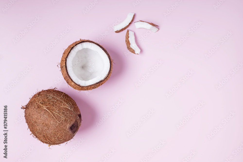 Coconuts whole and half on pink background, top view.