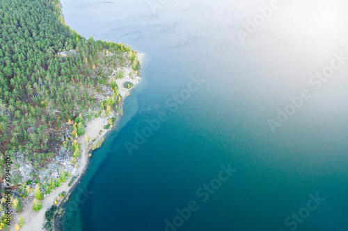 Aerial view of blue lake with green forests with rocks on a summer day