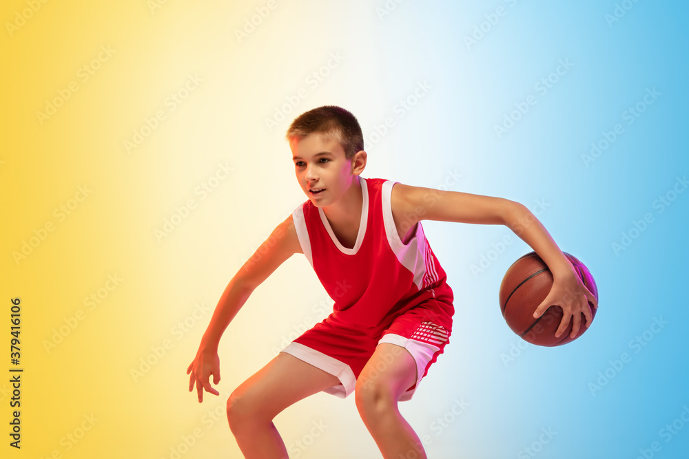 Hurry up. Portrait of young basketball player in uniform on gradient studio background. Teenager confident practicing with ball. Concept of sport, movement, healthy lifestyle, ad, action, motion. Hurry up. Portrait of young basketball player in uniform on gradient studio background. Teenager confident practicing with ball. Concept of sport, movement, healthy lifestyle, ad, action, motion.