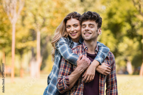 woman embracing man in checkered shirt in park © LIGHTFIELD STUDIOS