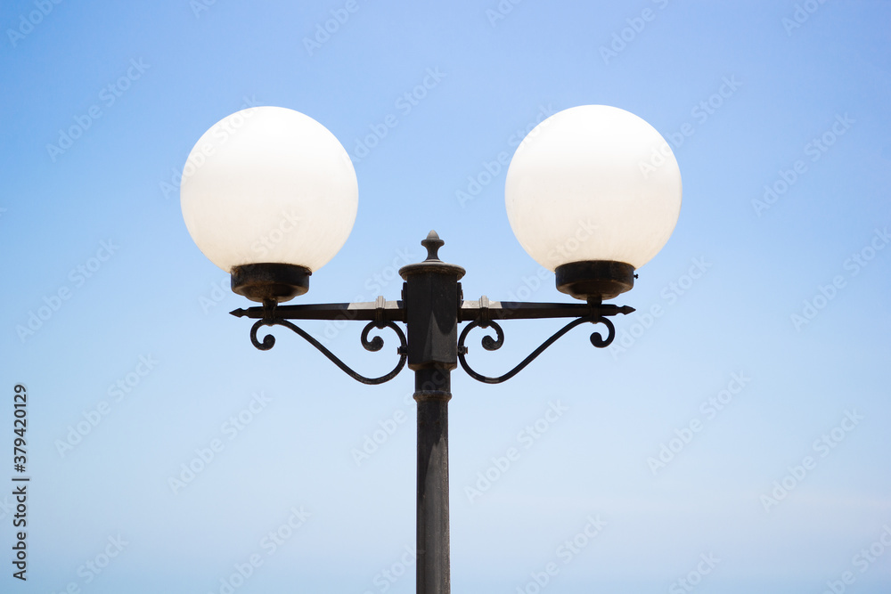 Round lamp on pole, outdoor lighting on clear blue sky.Photos of white lanterns taken on the street outside the residence. Round lamp on pole, outdoor lighting on clear blue sky.Photos of white lanterns taken on the street outside the residence.