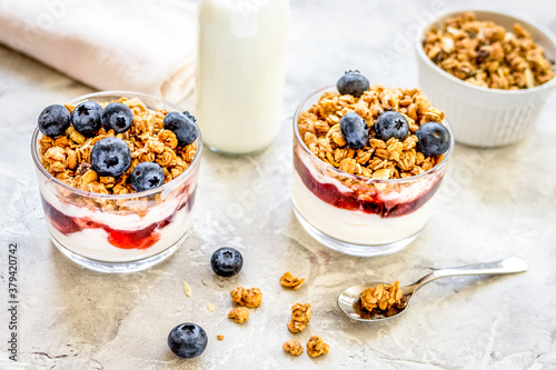 Morning granola in glass with yogurt, honey and milk on white desk