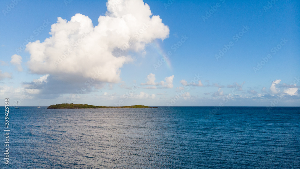 Rainbow over the ocean with island and clouds, drone shot Rainbow over the ocean with island and clouds, drone shot