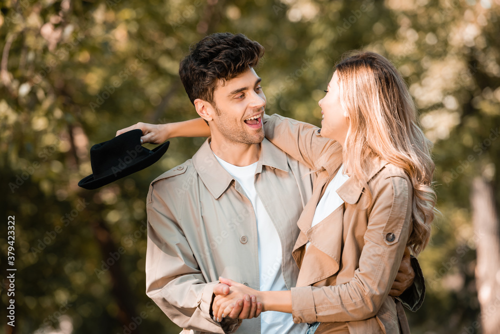 Fototapeta premium excited couple holding hands and and looking at each other in autumnal park