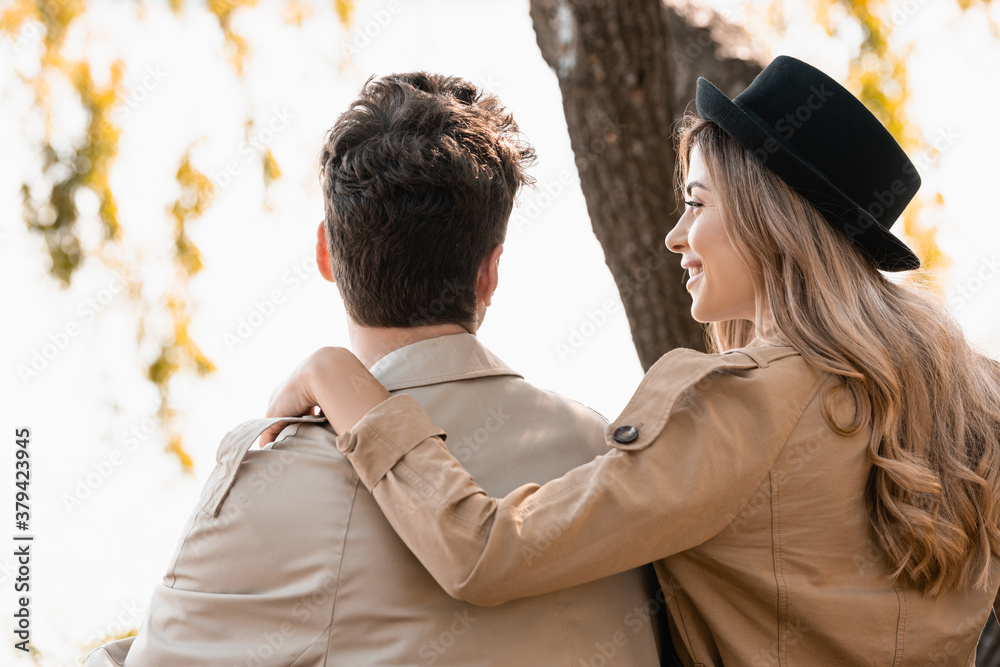 Fototapeta premium blonde woman in hat touching and looking at boyfriend outside