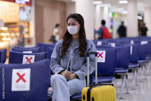 Asian young woman traveller wearing face maks at airport Due Covid-19 flu virus pandemic and protection