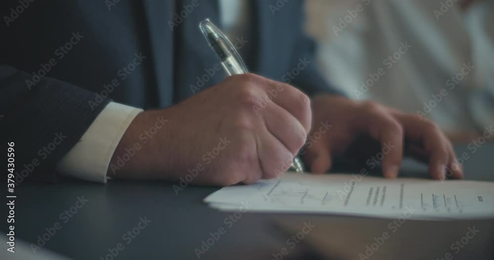 Close up of a businessman's hands signing a contract during a business meeting. Slow motion
